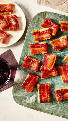 bacon strips on a plate next to a glass of red wine and two plates with sauces