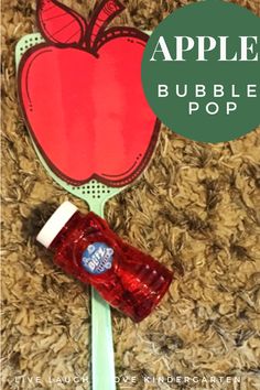 an apple shaped bubble pop on a green plastic spoon with a red cup next to it