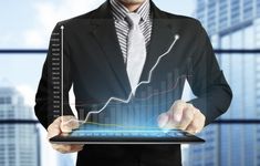 a man in a business suit is holding a tablet with an upward graph on it