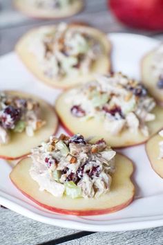 small appetizers are arranged on a plate with apples in the background and other food items