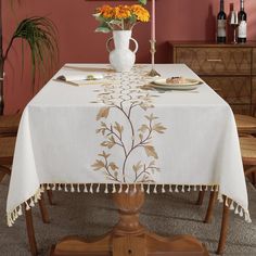 a dining room table with a white vase and flowers on it, along with other furniture