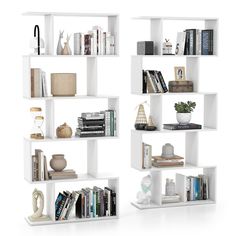 three white bookshelves with different types of books on top of each shelf and various decorations