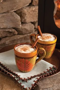 two mugs filled with coffee sitting on top of a table