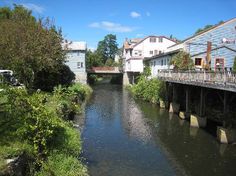 a river running through a small town with houses on either side and a bridge over it