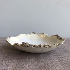 a white bowl sitting on top of a wooden table next to a wall and floor