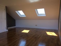 an empty room with wooden floors and skylights