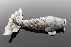 an origami fish made out of money is floating in the water with words written on it