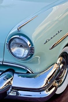 the front end of an old fashioned car with chrome rims and headlamps