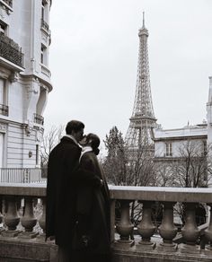 a man and woman standing next to each other near the eiffel tower in paris