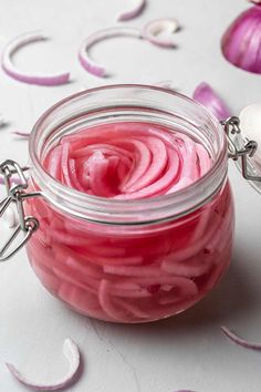 a jar filled with pink jello sitting on top of a table next to sliced onions