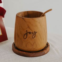 a wooden bowl with the word joy written on it next to a small red box