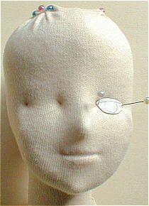 a white mannequin head with pins on it