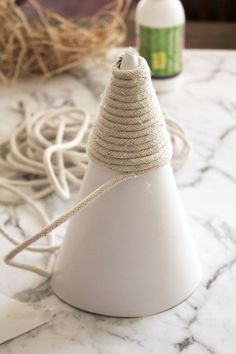 a white cone with rope wrapped around it sitting on a marble counter top next to other items