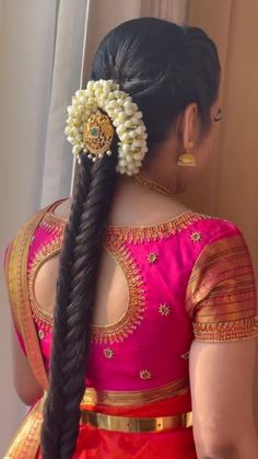 a woman with long black hair wearing a pink sari and gold broochel