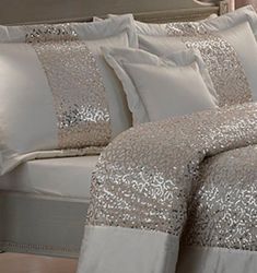 a bed with white sheets and silver sequins on the comforter is shown