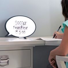 a person writing on a piece of paper in front of a desk with a sign