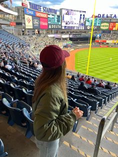 a woman standing in the bleachers at a baseball game looking out into the stands