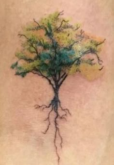 a tree tattoo on the back of a woman's leg with green and yellow leaves