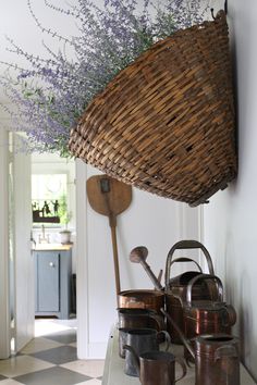 a basket hanging on the wall above pots and pans with lavender flowers in them