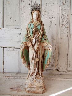 a statue of the virgin mary is shown in front of an old white wooden door