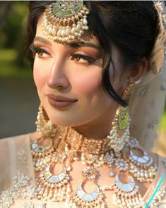 a woman in a bridal gown with jewelry on her neck and headpieces