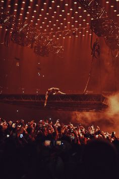 a man is performing on stage with his hands in the air while people are taking pictures