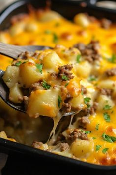 a casserole dish with cheese and ground beef being scooped from the casserole