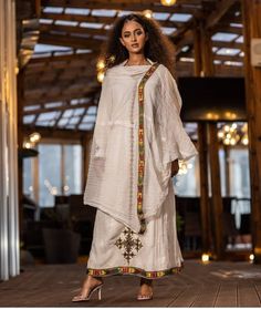 This stunning Ethiopian Habesha dress is made with handwoven Menen fabric, known for its luxurious feel and traditional craftsmanship. The vibrant colors of the dress, paired with intricate Tilf embroidery at the neckline and wrists, make for a truly eye-catching piece. The dress is designed to be comfortable and flattering, with a flowing skirt and flattering waistline. Perfect for any special occasion, this dress is a true testament to the beauty and richness of Ethiopian fashion. PLEASE ADD Y Traditional Cotton Silk Kaftan For Festivals, Designer Tussar Silk Straight Kurta Dress, Embroidered Slub Silk Saree Dress, Bohemian Cotton Silk Sets For Spring/fall, Traditional Raw Silk Kaftan For Designer Wear, Bohemian Chanderi Sets In Traditional Drape, Festive Embroidered Slub Silk Dress, Bohemian Cotton Silk Traditional Wear For Navratri, Traditional Embroidered Cotton Silk Kaftan