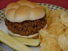 a plate with a sandwich, pickle and chips on it