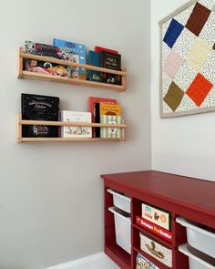 two wooden bookshelves on the wall above a red desk with bins underneath