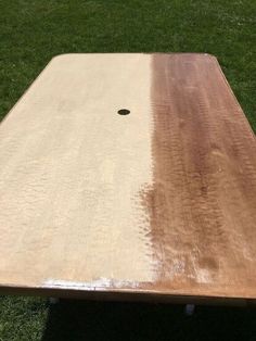 a large wooden table sitting on top of a green grass covered field with a hole in the middle