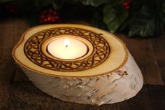 a lit candle sitting on top of a piece of wood