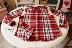 a red and white plaid shirt sitting on top of a table next to a pair of scissors