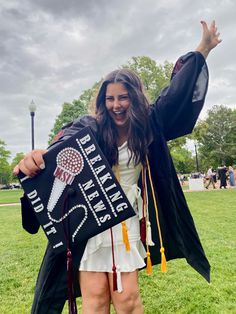 a woman in graduation gown holding up a sign