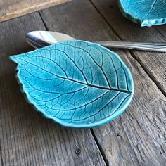 a blue plate with a leaf design on it and two spoons next to it