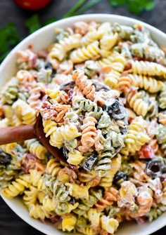 bacon ranch pasta salad in a white bowl with a wooden spoon