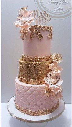 a pink and gold wedding cake with flowers on top