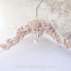 a wedding dress hanging from a hanger with pearls and bows on it's back