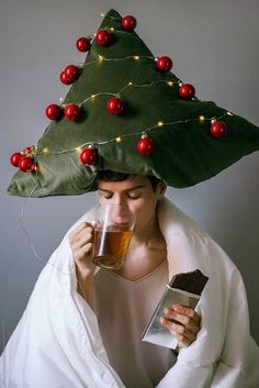 a woman wearing a christmas tree hat drinking tea