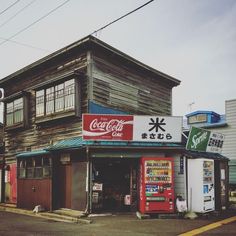 an old wooden building with coca cola signs on the front and side of it's storefront