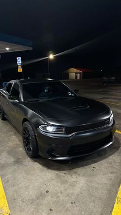 a black dodge charger parked in a parking lot at night with the lights on