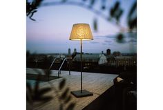 a lamp sitting on top of a wooden table next to a swimming pool