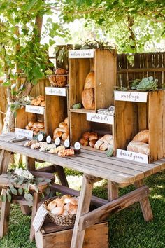 a wooden table topped with lots of different types of bread on display next to a tree