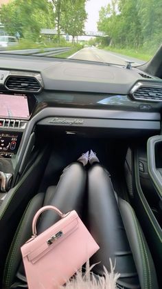 a pink purse sitting in the center of a car's dashboard, next to a handbag