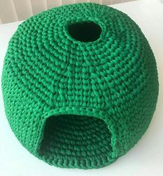 a green knitted cat bed sitting on top of a white table