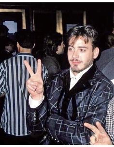 two men sitting next to each other in front of a crowd holding up peace signs