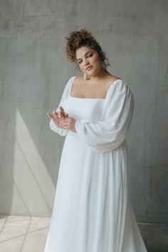 a woman in a white dress is posing for the camera with her hands clasped up