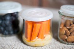 three jars filled with nuts and carrots next to each other