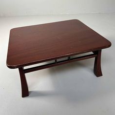 a small wooden table with two legs and a square shaped top on the bottom, against a white background