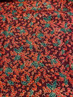 an orange and green floral print fabric with red flowers on dark purple background, closeup